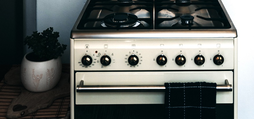 A clean and tidy gas stove with glistening silver knobs and a fresh kitchen towel.